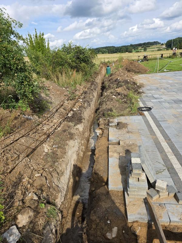 Wykop pod podmurówkę ogrodzenia z przygotowanym zbrojeniem