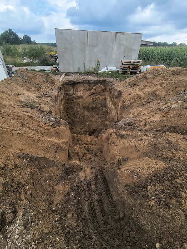 Szeroki, gotowy wykop obok ściany budynku